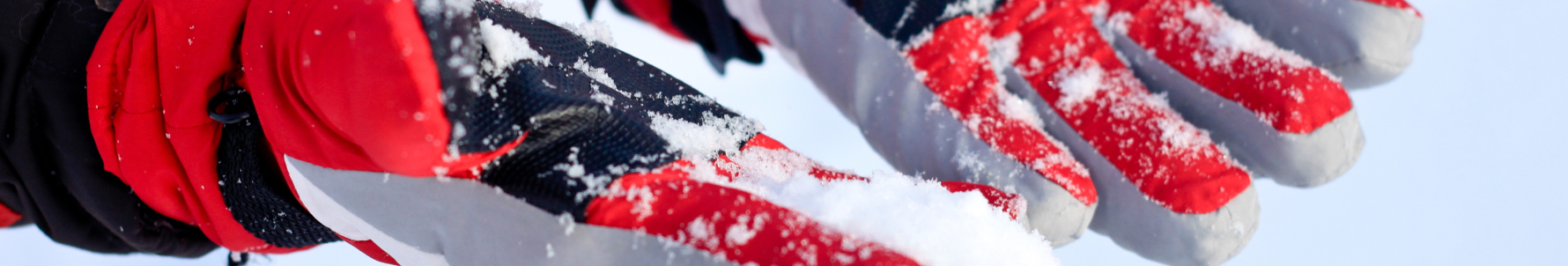 : Kciuk narciarza - dłonie w zaśnieżonych rękawicach narciarskich.