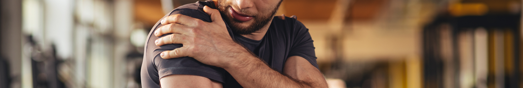 Rabdomioliza - młody mężczyzna trzymający się za mięsień ramienia.